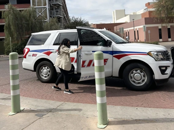 Patti Norris, UA mental health clinician, stands next to a UAPD car. 