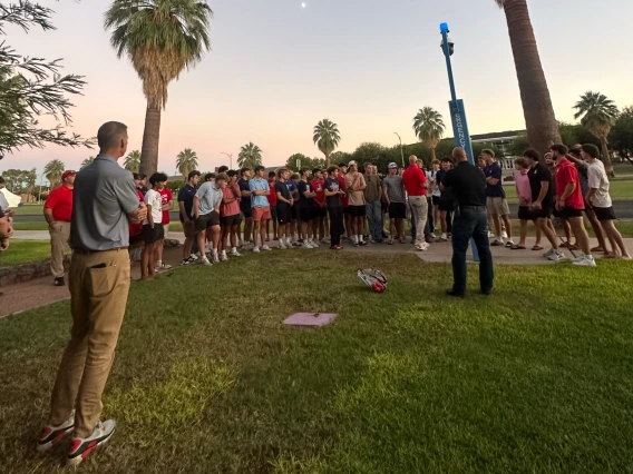 A group of students on a Safety Stroll are standing near a blue light phone on campus. Chief Olson is speaking with them.