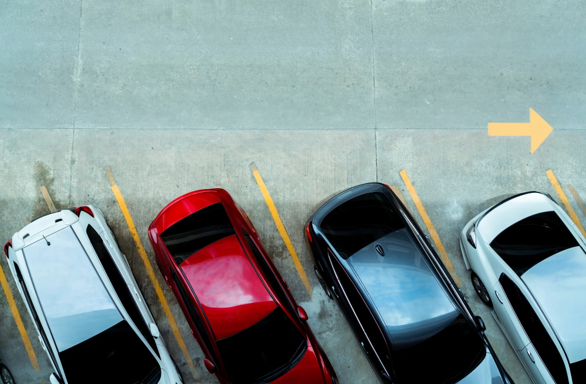 Overhead view of 4 cars parked diagonally in a parking lot.