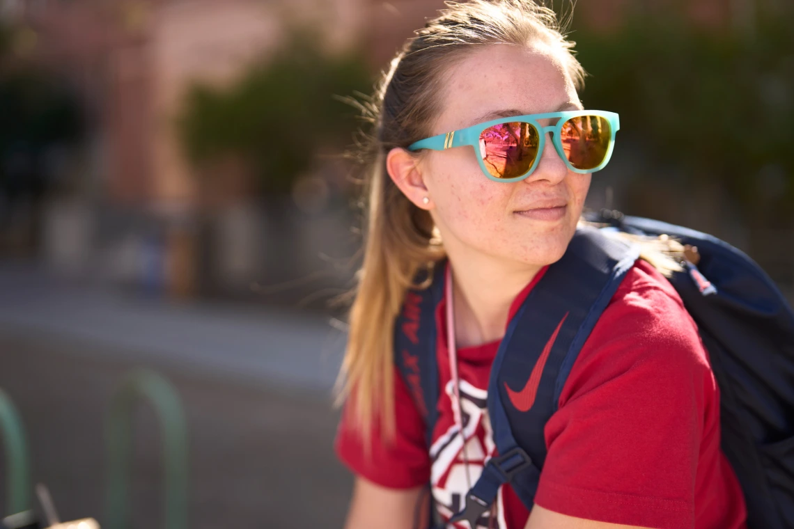 Student wearing reflective sunglasses sitting on UA Mall.