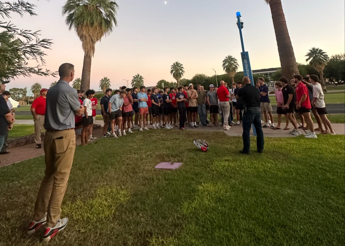 A group of students on a Safety Stroll are standing near a blue light phone on campus. Chief Olson is speaking with them.