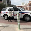 Patti Norris, UA mental health clinician, stands next to a UAPD car. 